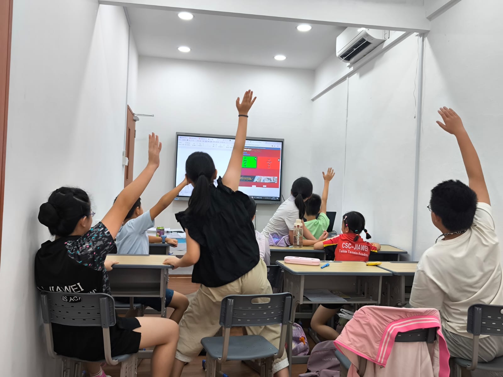 Image of students raising hands to answer questions in Oxkids Learning Centre