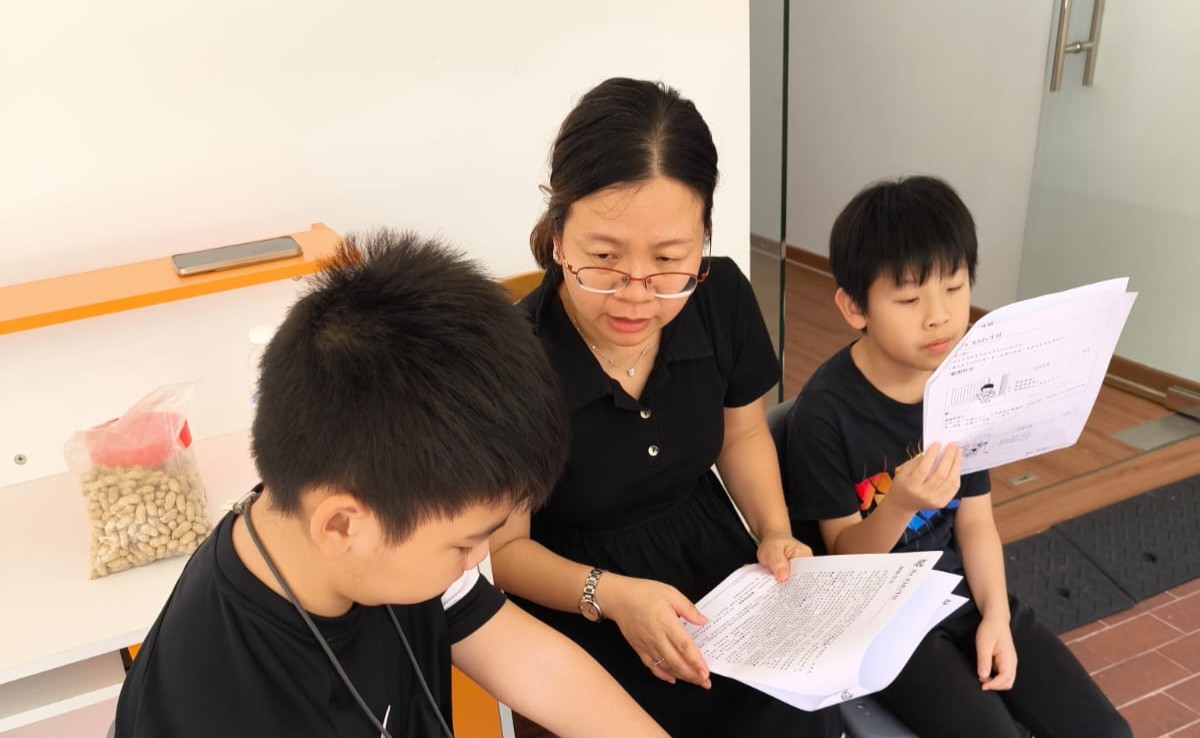 Image of teacher and 2 students from Oxkids going through a paper